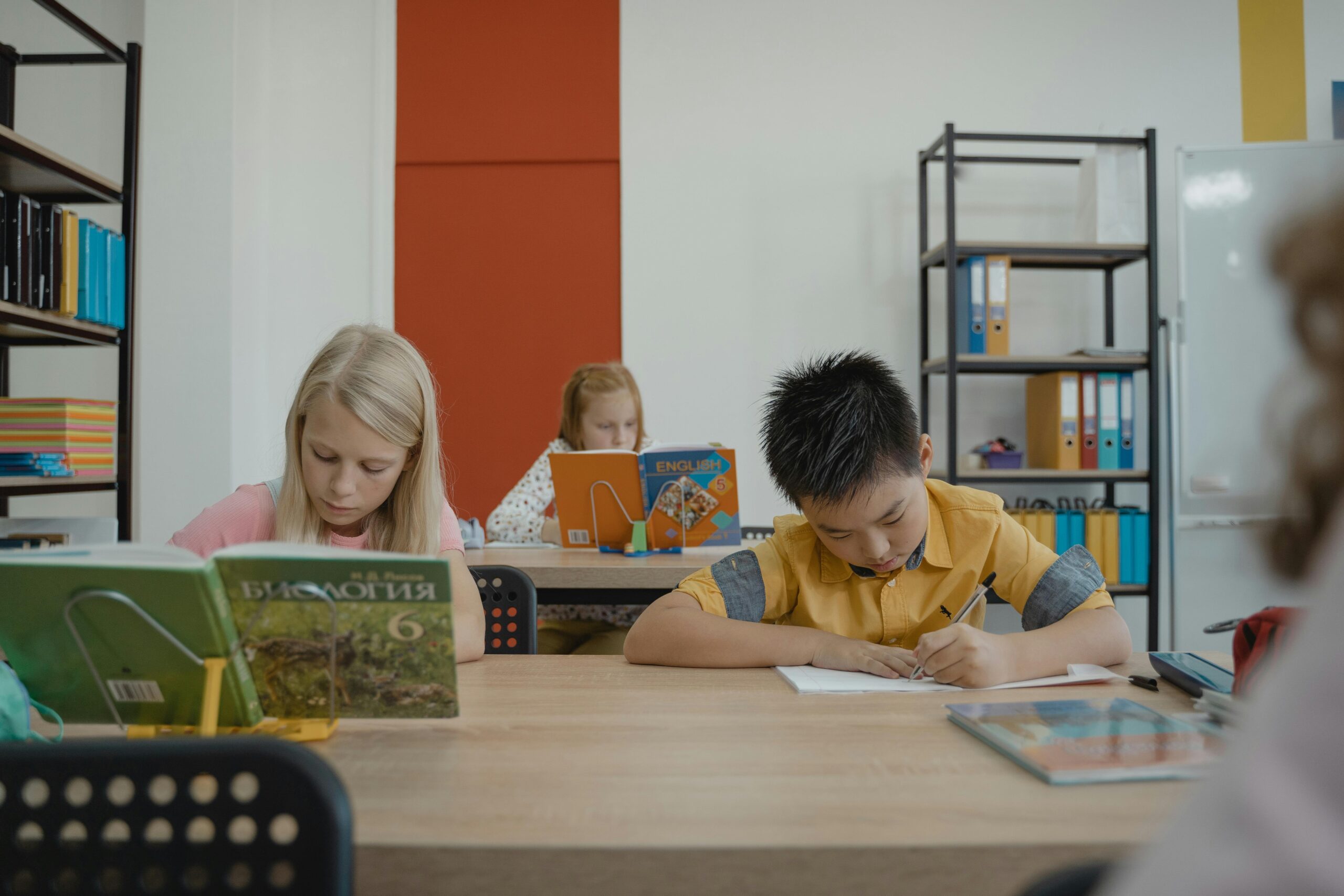 Students of different ethnicities focusing on studies in classroom, surrounded by books and notes.